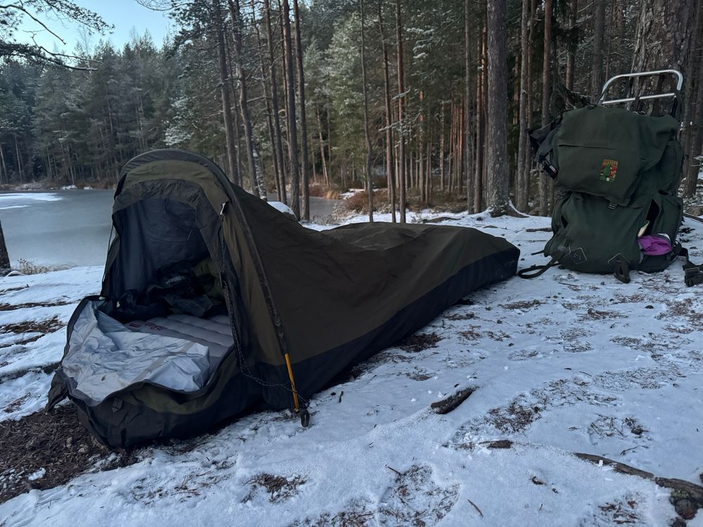 Bivouac-majoite ja rinkka lumisella maalla.