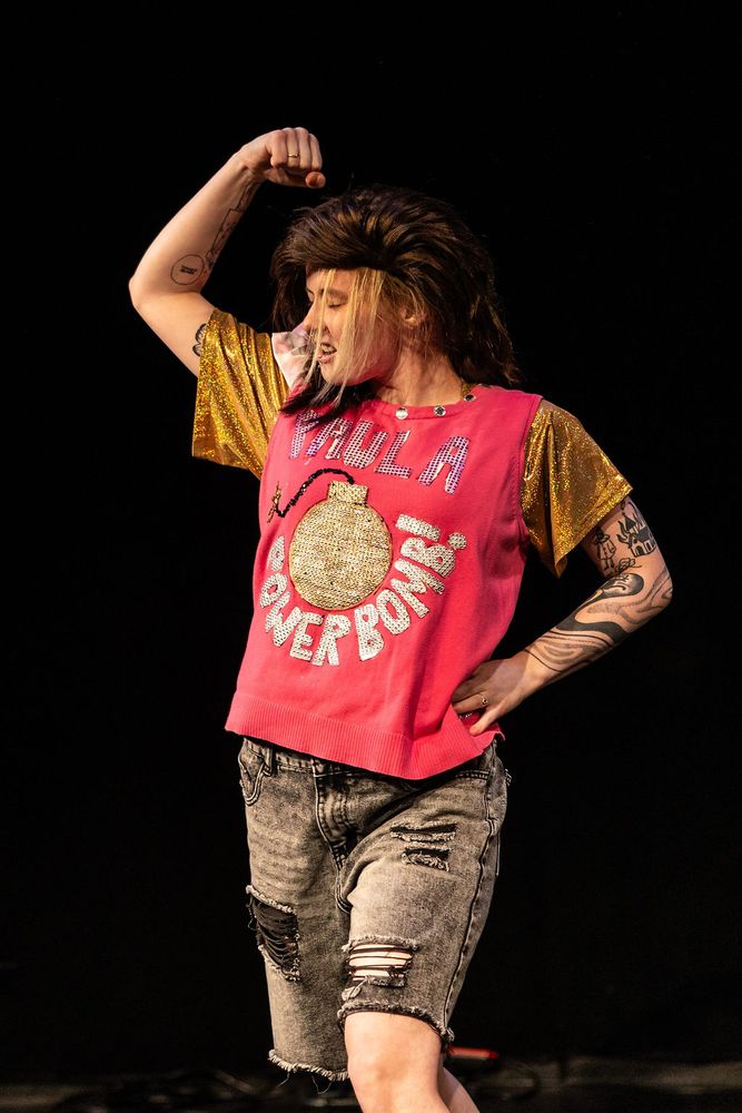 Milo shows off their alter ego, Paula Powerbomb!