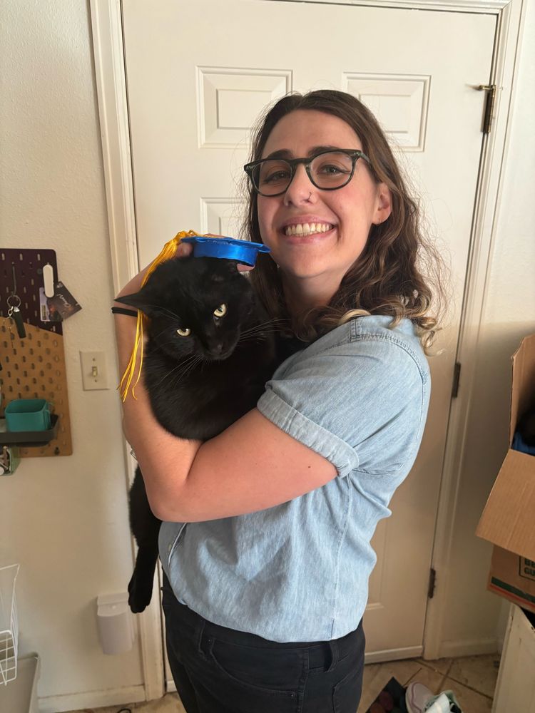 New PhD graduate holding a cat wearing a graduation cap