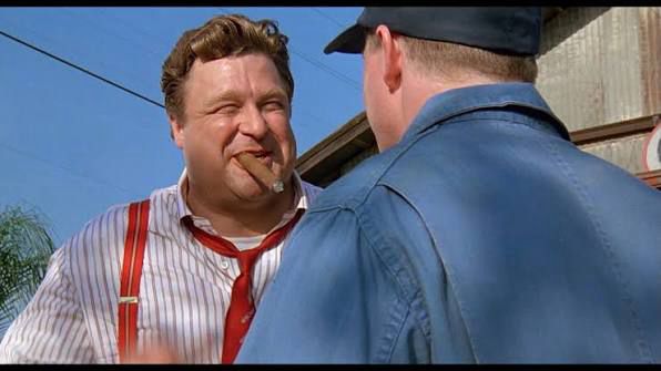 John Goodman chomping on a cigar and grinning.