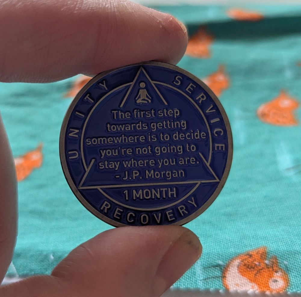 Other side of the same coin. It says "The first step towards getting somewhere is to decide you're not going to stay where you are." J.P. Morgan. Unity, Service, Recovery. 1 MONTH.