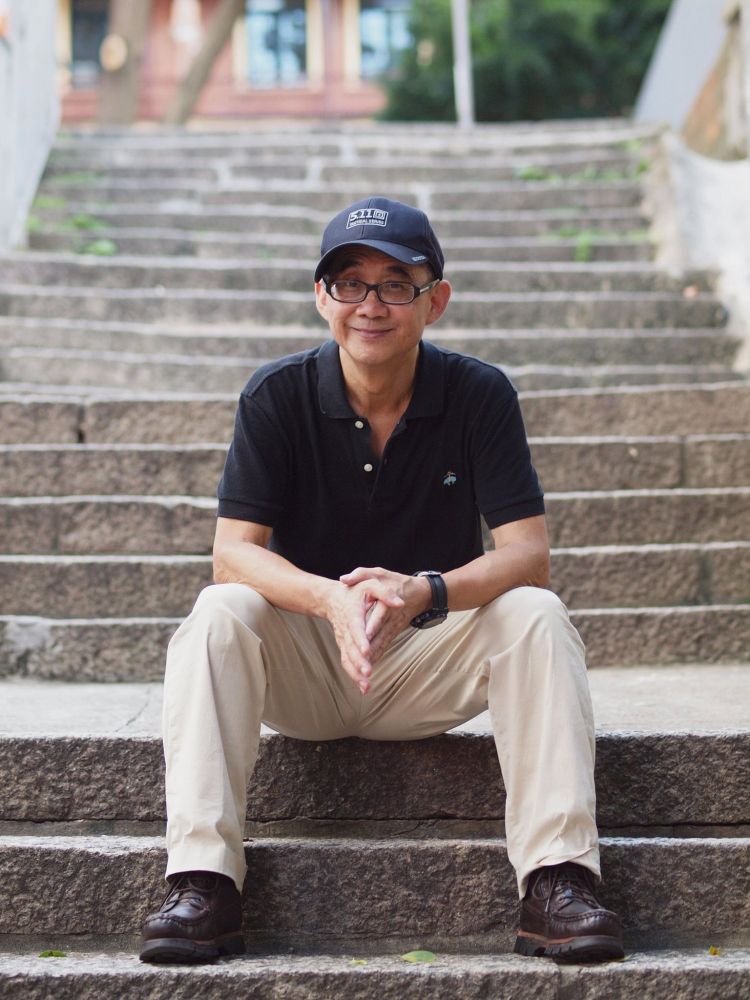 A photo of the poet Yam Gong sitting on steps.