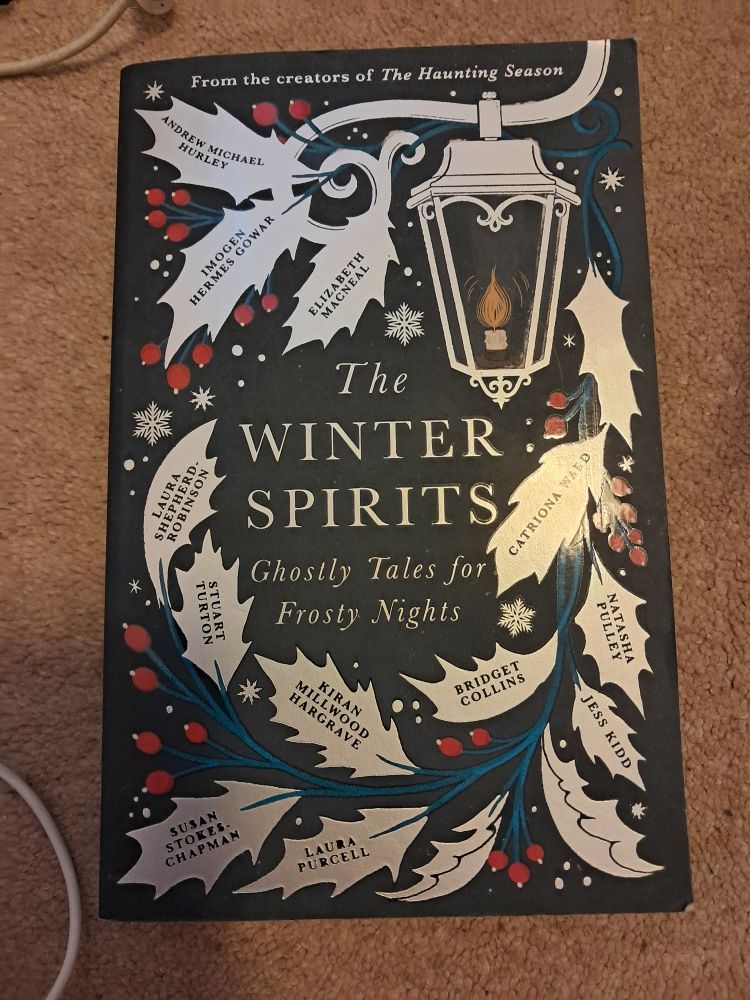 The book cover of The Winter Spirits. White holly leaves on a black background.