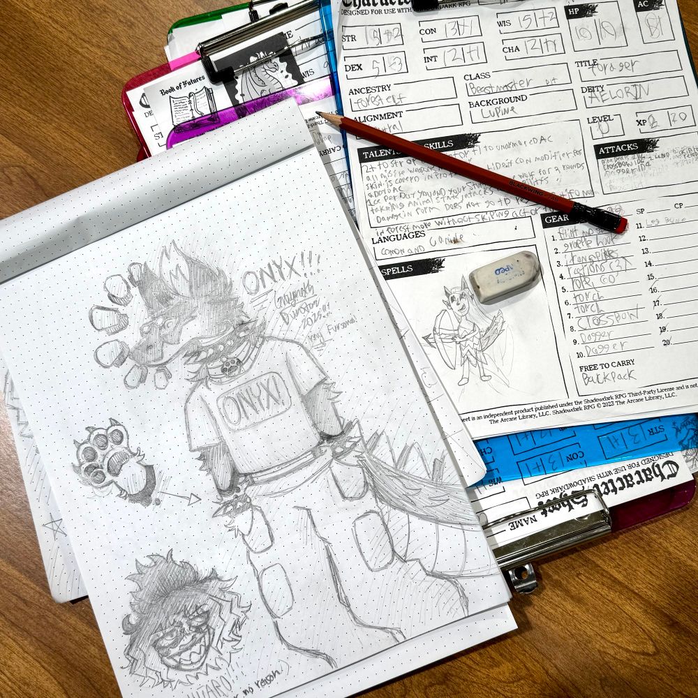 Drawing pad and character sheets on a table.