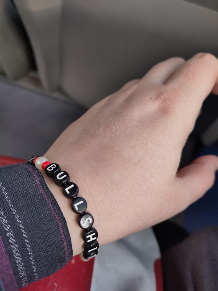 Picture of a wrist wearing a bracelet reading "MARDU BULLSHIT" in red, white and black.