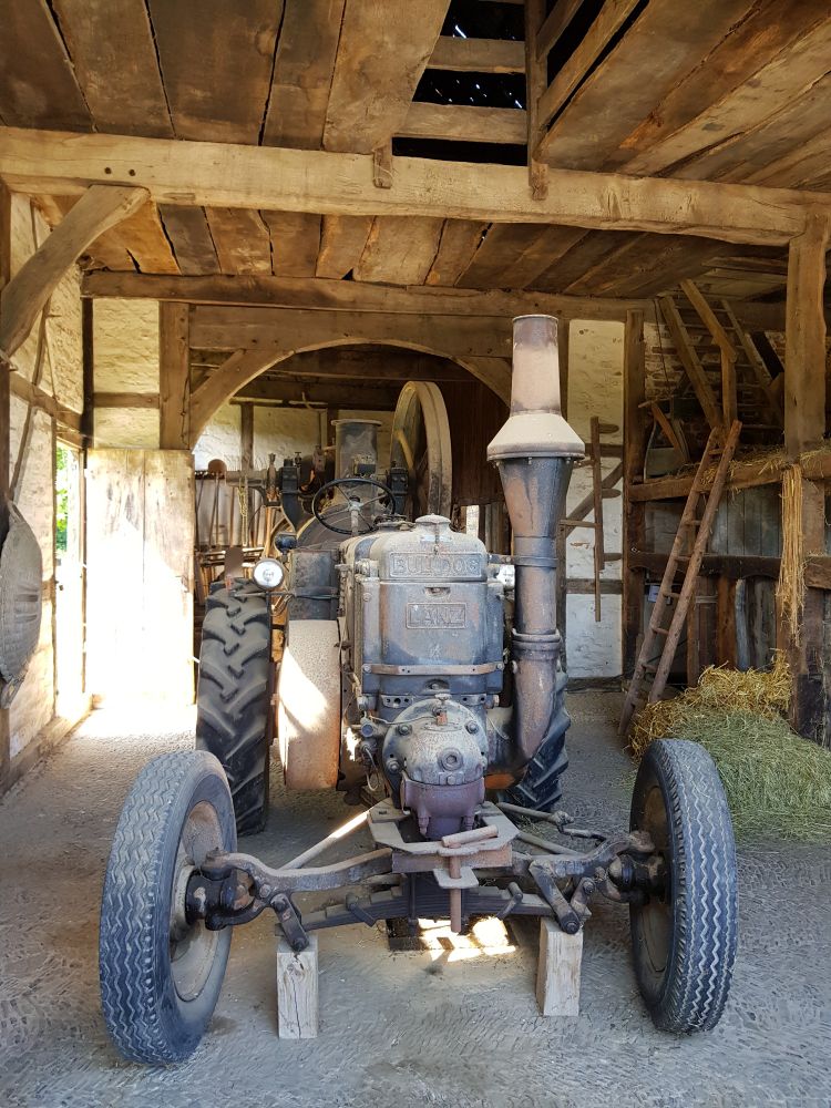 Ein historischer Traktor "Lanz Bulldog" in einer alten Holzscheune. Der Traktor ist stark verrostet und sehr verstaubt. 