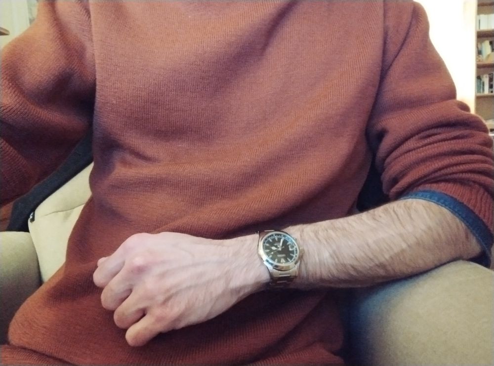 Même photo que plus haut quasiment mais cette fois je suis accoudé sur mon bras droit dont la manche est relevée, et auquel je porte une montre noire à bracelet métallique 
