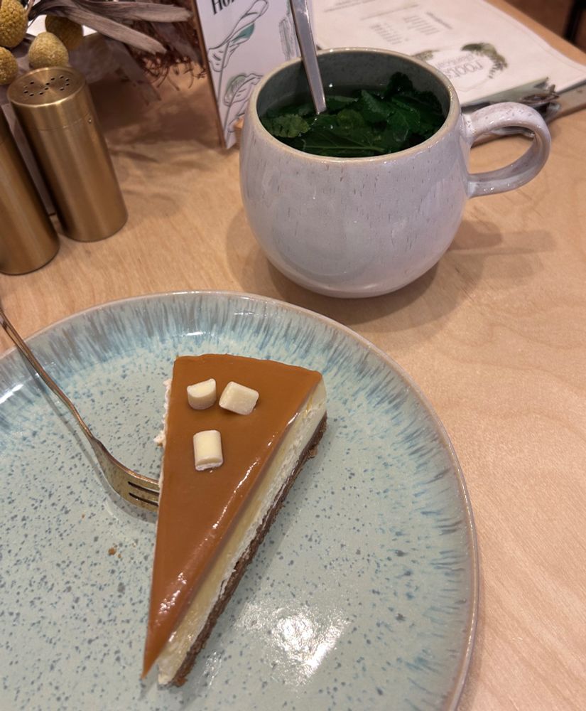 Ein heißer Minztee und ein Stück Kuchen sind auf einem tisch platziert. 