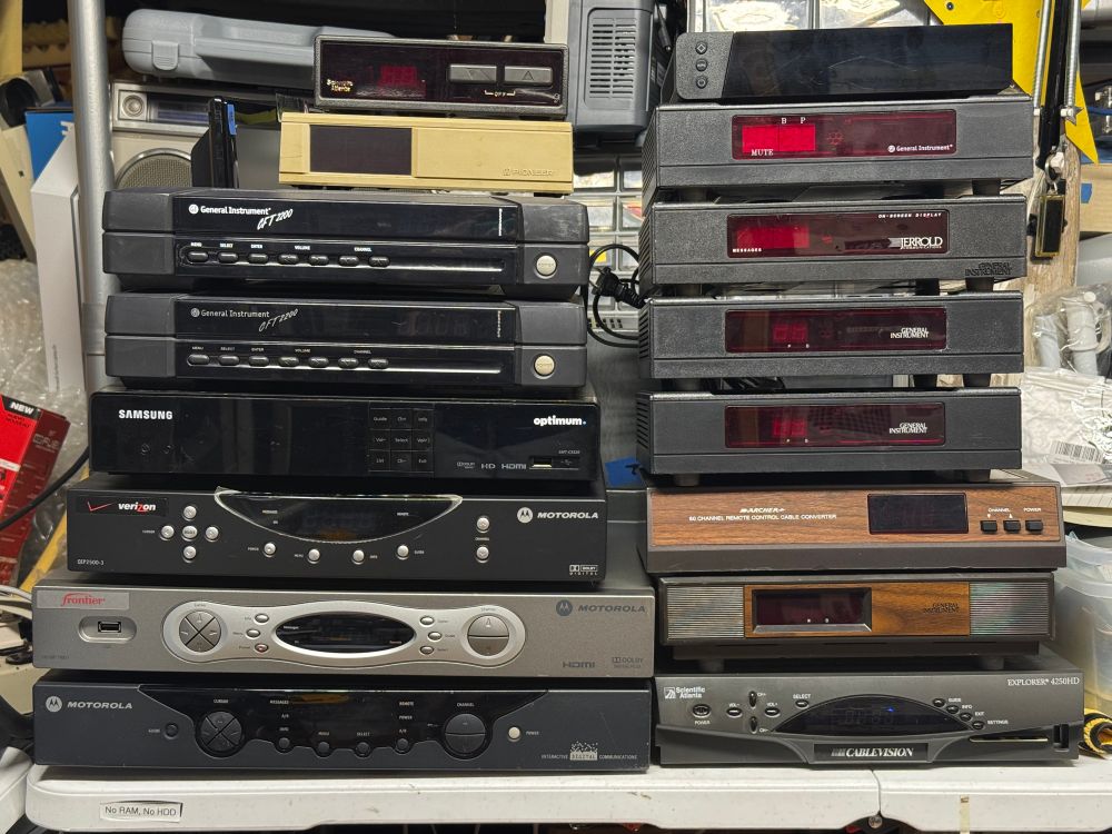 A stack of various cable boxes from Motorola, Jerrold, Scientific Atlanta, and more