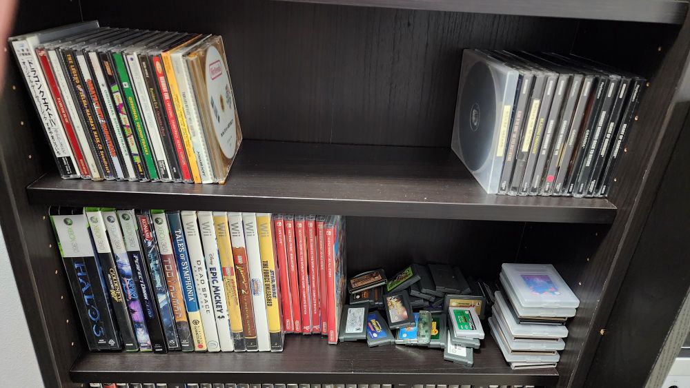 Two bookshelves with video game OST music CDs, PlayStation games, Xbox 360, Wii, Switch, GameBoy, and GameBoy Advance games.