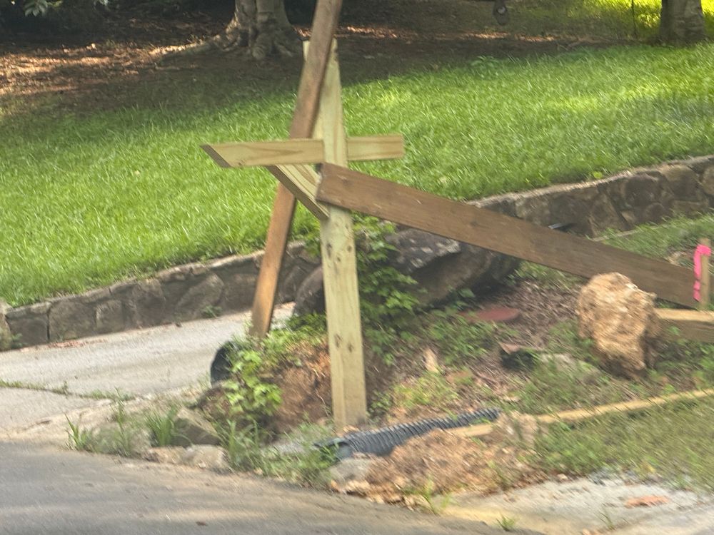 mailbox post with boards randomly bolted on either side, kind of holding it up but at a crazy angle