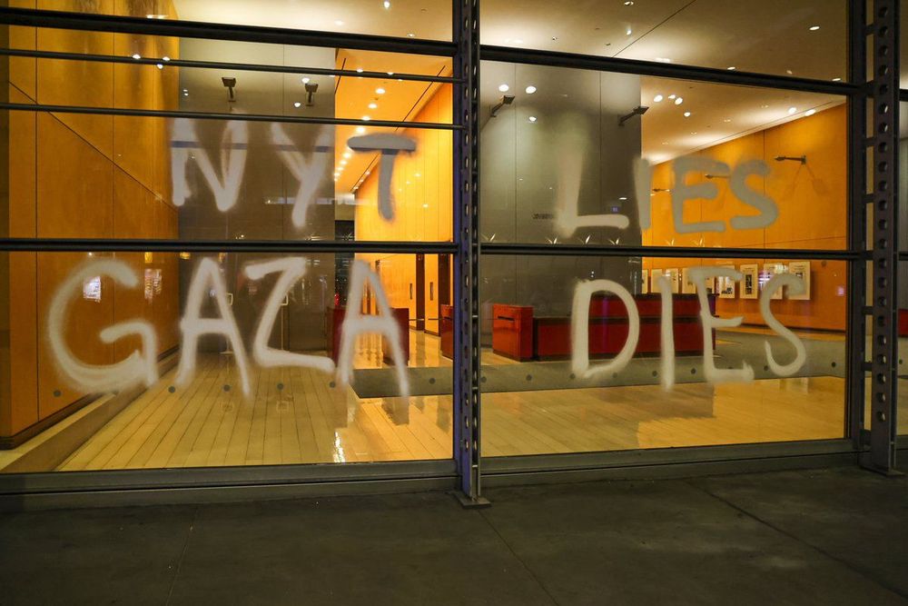 Windows of the gray lady building spray-painted with “NYT LIES GAZA DIES”
