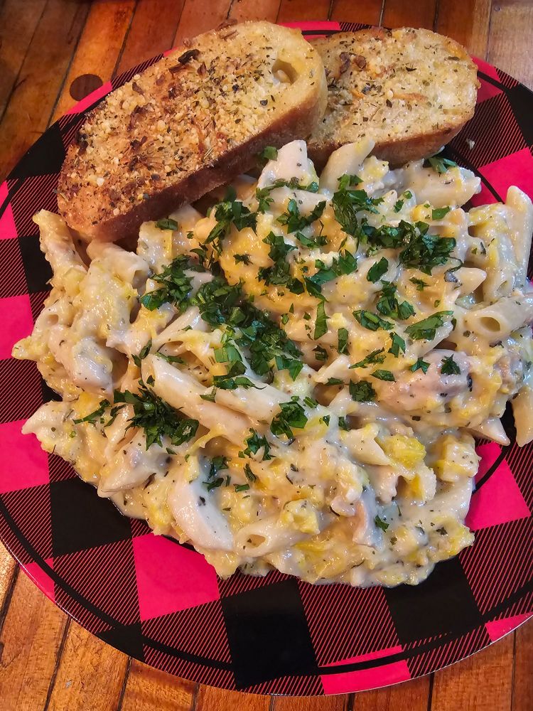 Creamy Alfredo with bits of pumpkin and chicken among penne pasta, garnished with parsley. Served alongside toasted garlic bread.