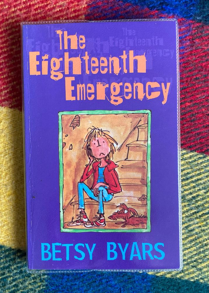 The book, The Eighteenth Emergency by Betsy Byars. Cover illustration, by Quentin Blake, is a glum looking boy wearing jeans and a red jacket, sitting on the bottom stair. Beside him is a scruffy brown sausage dog.
