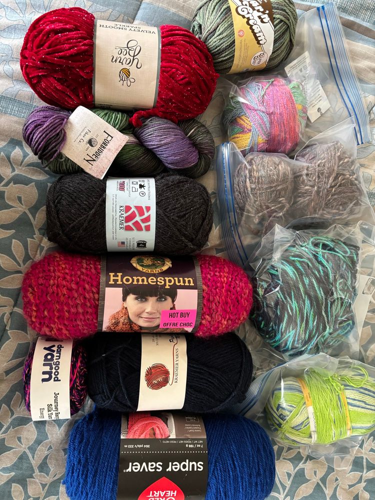 Twelve full skeins of yarn. If it looks like I did something with it, it means I started a thing and then frogged it, but didn't cut any off. No labels for the brown and the black & greenish next to it. (The brown was a gift so I don't have further info but I can tell you where I got the other one so you can check the site.)