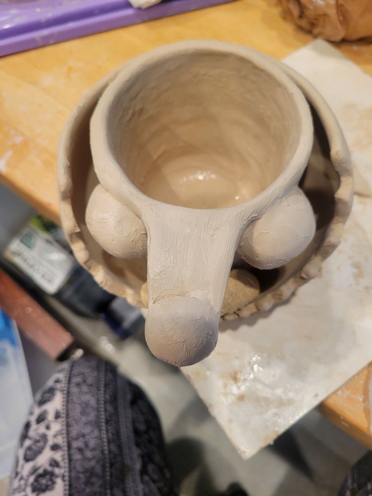A mug and plate that when together resemble a googly eyed angler fish tow down view.