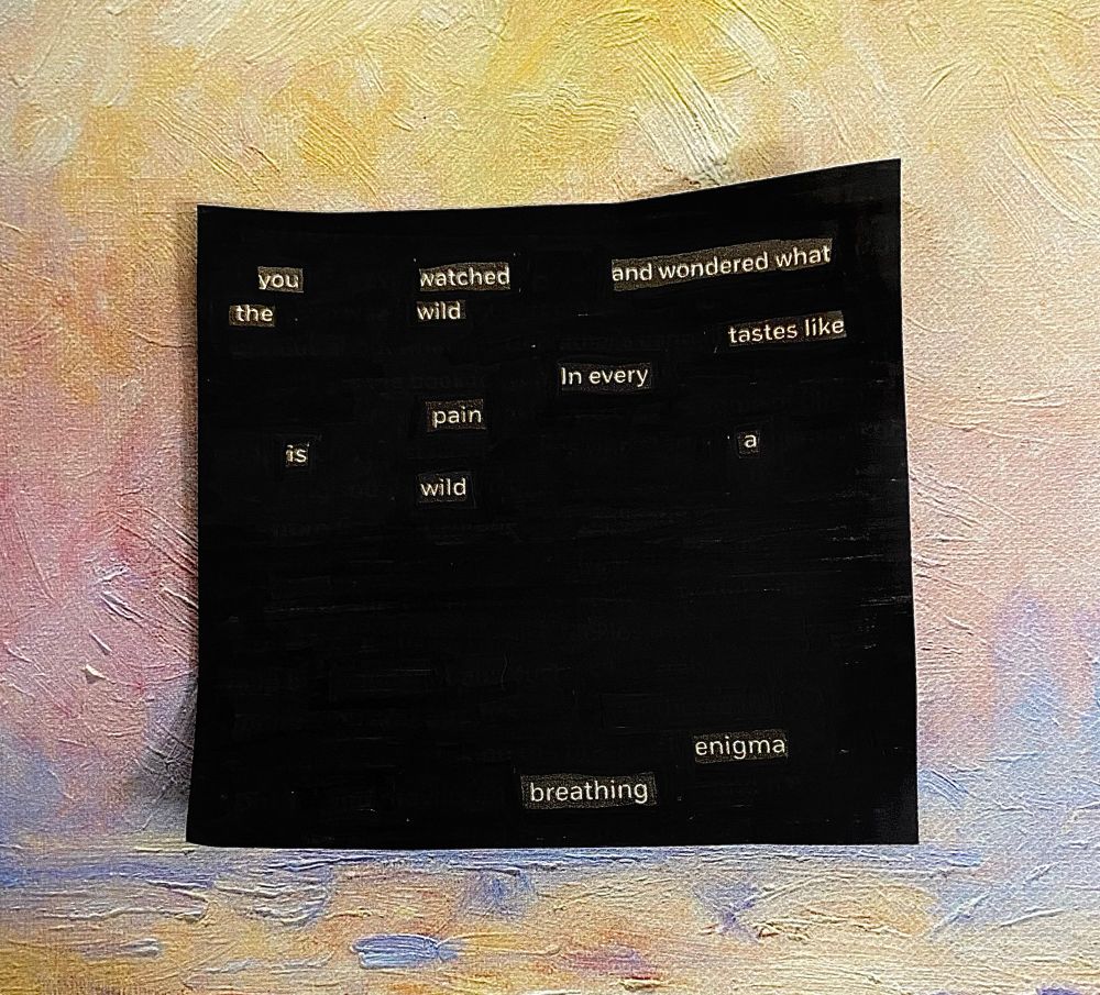 A photo of a blackout poem (a page of printed text in which all words except for those intended to be included as a poem are blacked out) laid on a pastel painted (notebook cover) background. 
The poem reads: “you watched and wondered what the wild tastes like / in every pain is a wild enigma breathing”