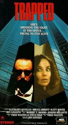 The poster for the movie trapped. A man and a woman contrasting against a high rise tower behind them.