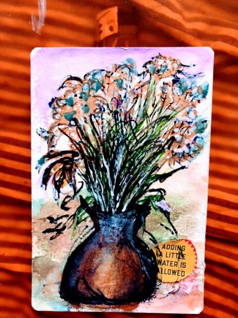 Ein buntes bemaltes tongefäss das mit bunten Blumen bestückt ist 