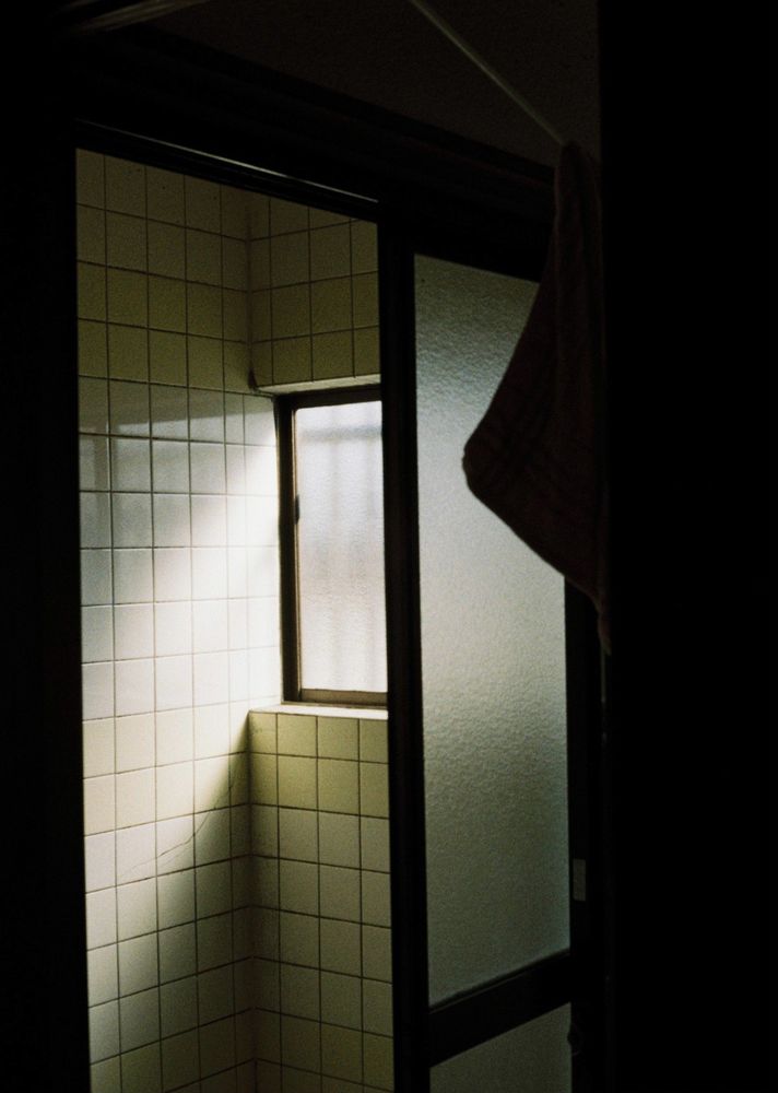 風呂場のすりガラス戸が半分空いて風呂場が見えている写真。窓から柔らかな光が差し込んでいる