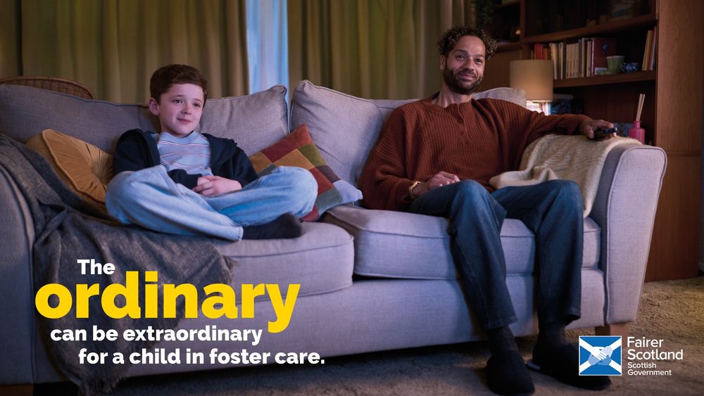 A young boy sits on the sofa next to a 