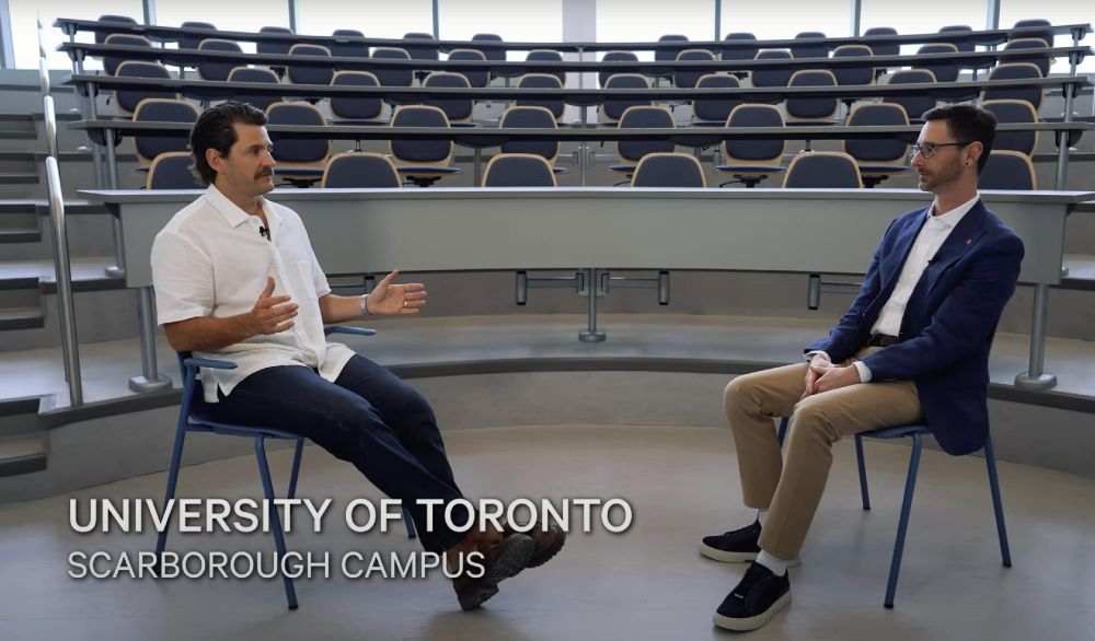 Two individuals sitting facing each other in a discussion inside a lecture hall at the University of Toronto Scarborough Campus.