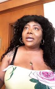 Woman with dark hair wearing a floral dress and a shocked expression 