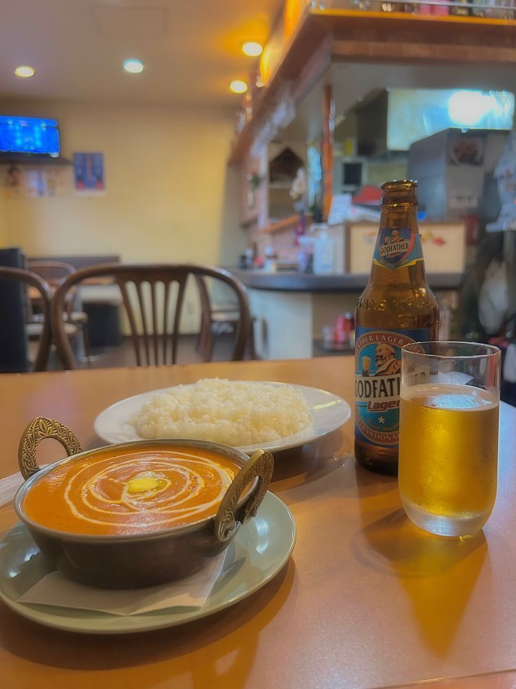 prato de comida indiana e ao lado uma cerveja indiana