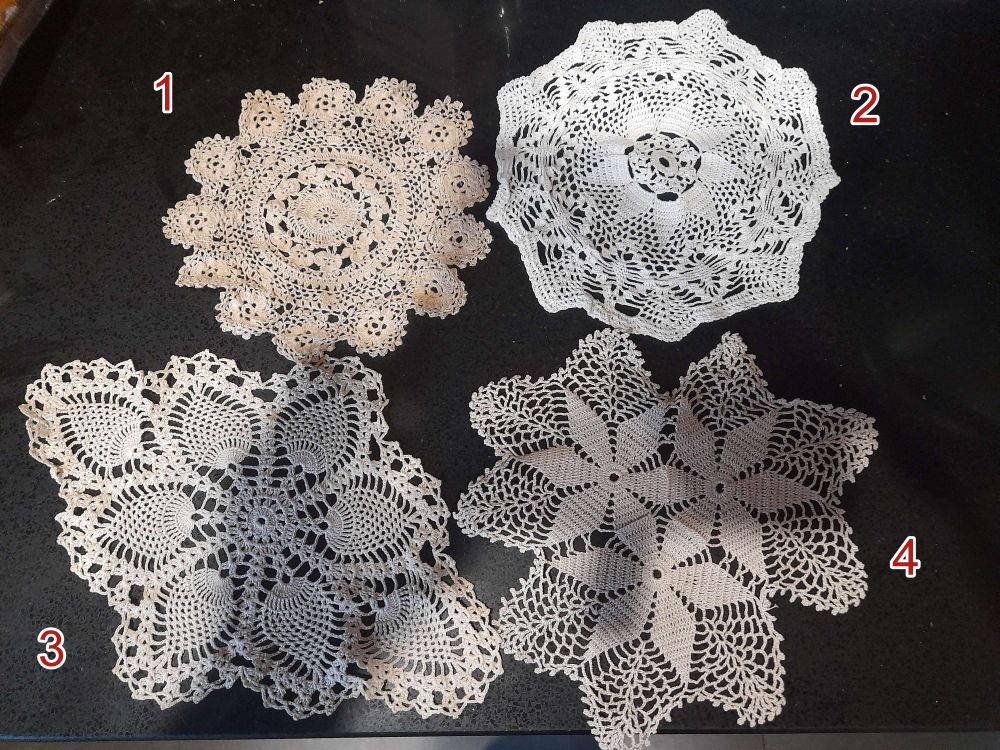 Four crochet doilies laid on a black counter top with the numbers 1-4 as options for picking. 