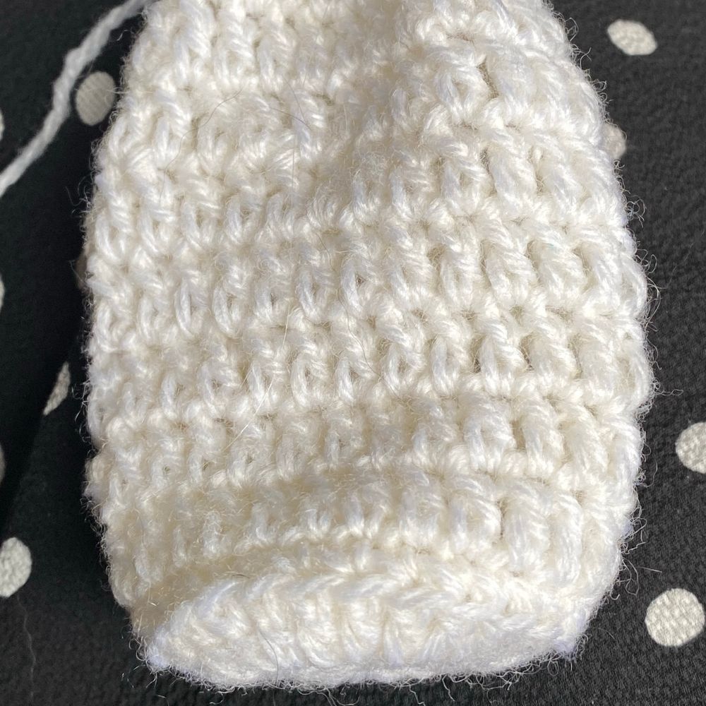 White crochet project on black with white spotted fabric