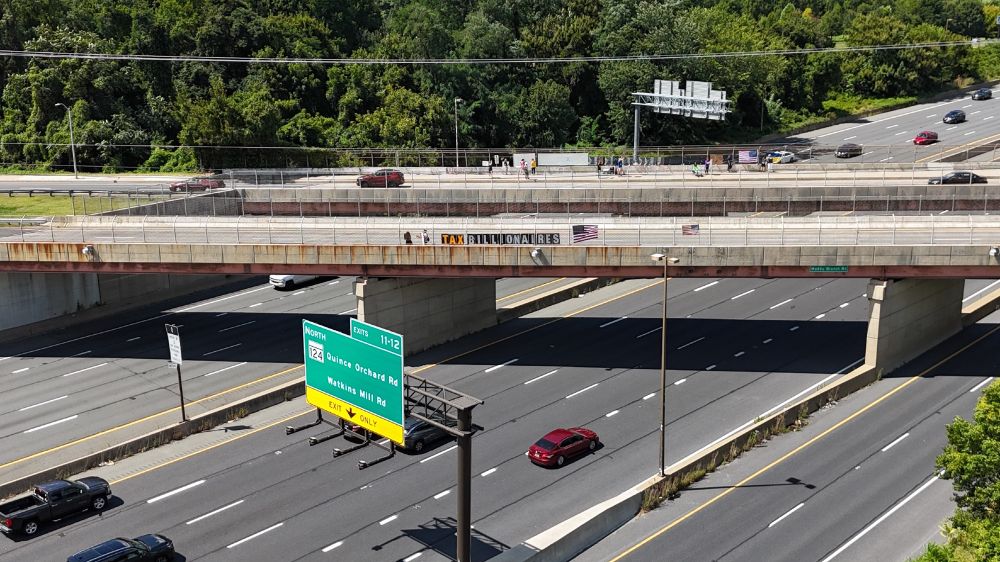 Protest signs on the fencing of an interstate overpass reading 