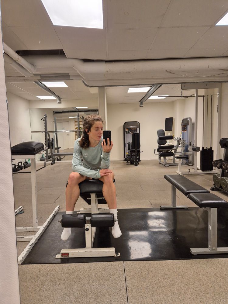 Spegelselfie i gymmiljö. Jag sitter så att man ser min överkropp, samt mina ben från knäna och nedåt