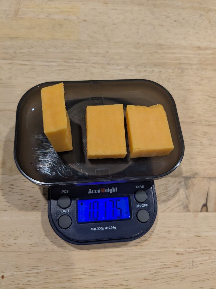 3 pieces of cheddar cheese on a scale weighing 1.0175 ounces