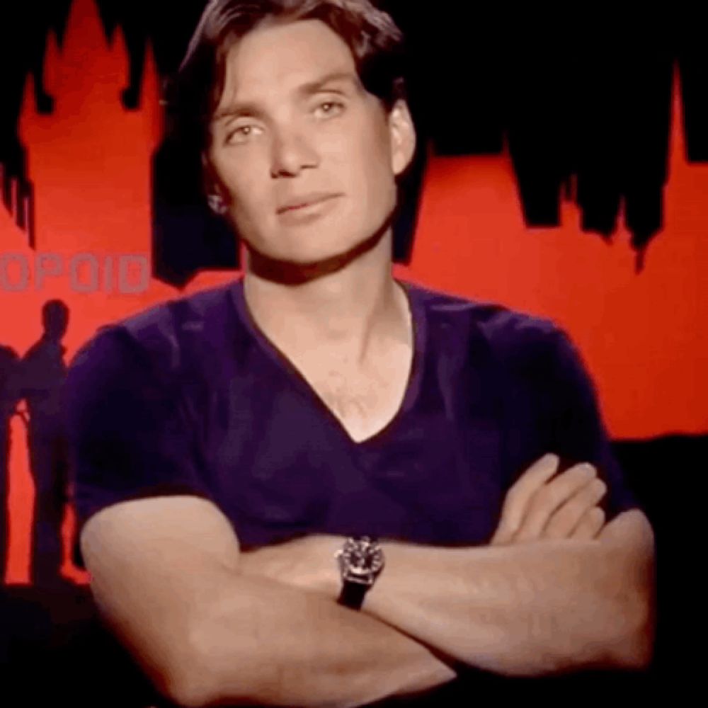 a man with his arms crossed is wearing a watch and a purple shirt