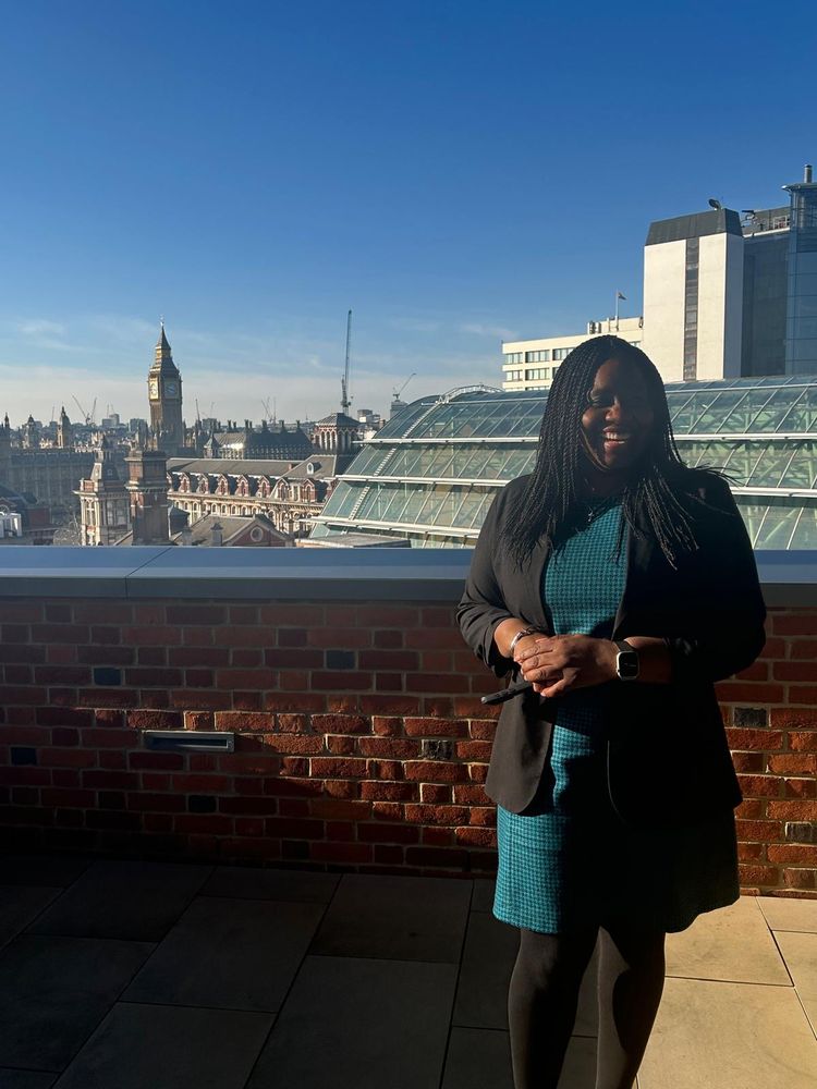 Marsha standing on a rooftop with a view of Parliament 