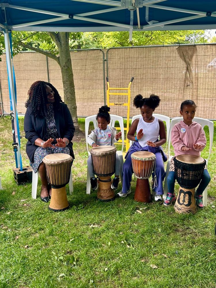 Marsha playing an African drum with three children