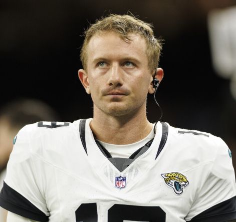 a white guy with short wavy blonde hair wearing a football jersey