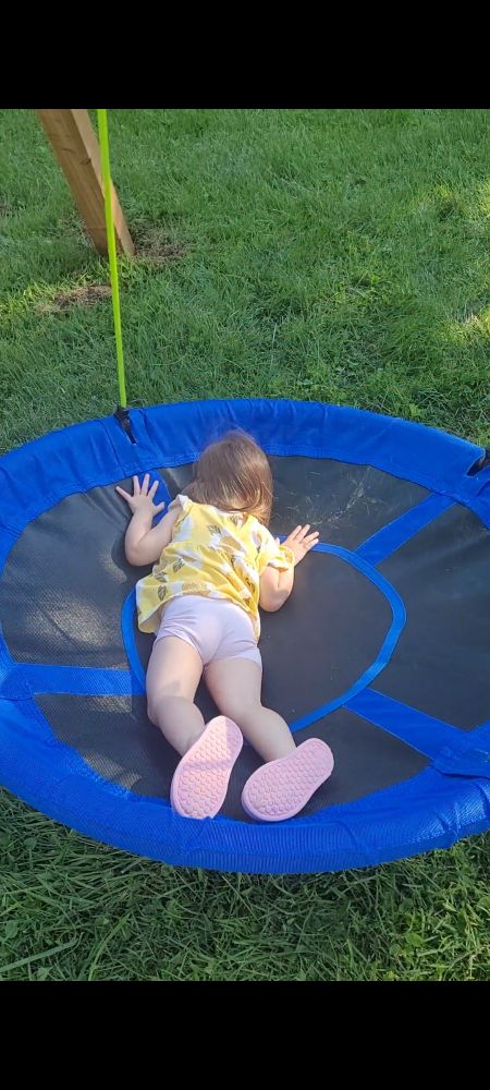 Girl laying face down on a swing. 