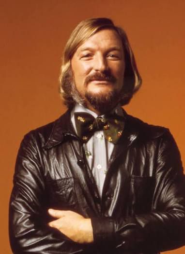James Last as The Master, in his blond bearded easy listening incarnation familiar costume of black leather jacket, light grey shirt and mockingly large black bow tie.