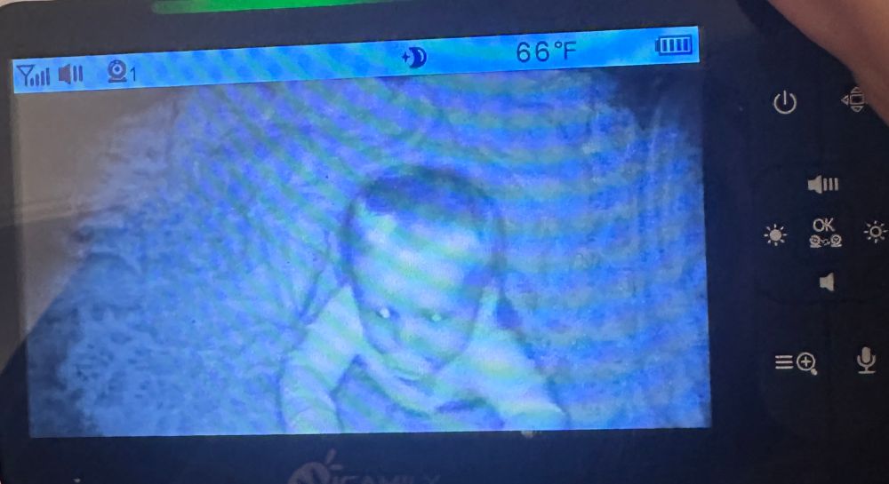 a baby standing and attempting to pull the cord out of a baby monitor device 
