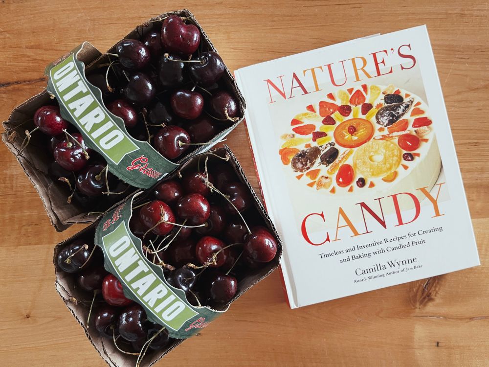 Two baskets of Ontario cherries beside the recipe book ‘Nature’s Candy’ by Camilla Wynne. 