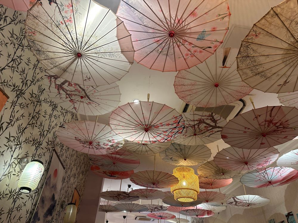 A ceiling covered in pretty hanging cherry blossom themed parasols.
