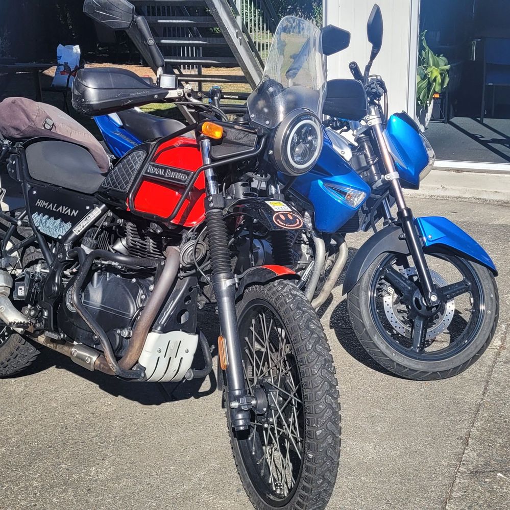 Two motorcycles parked outside a white building 