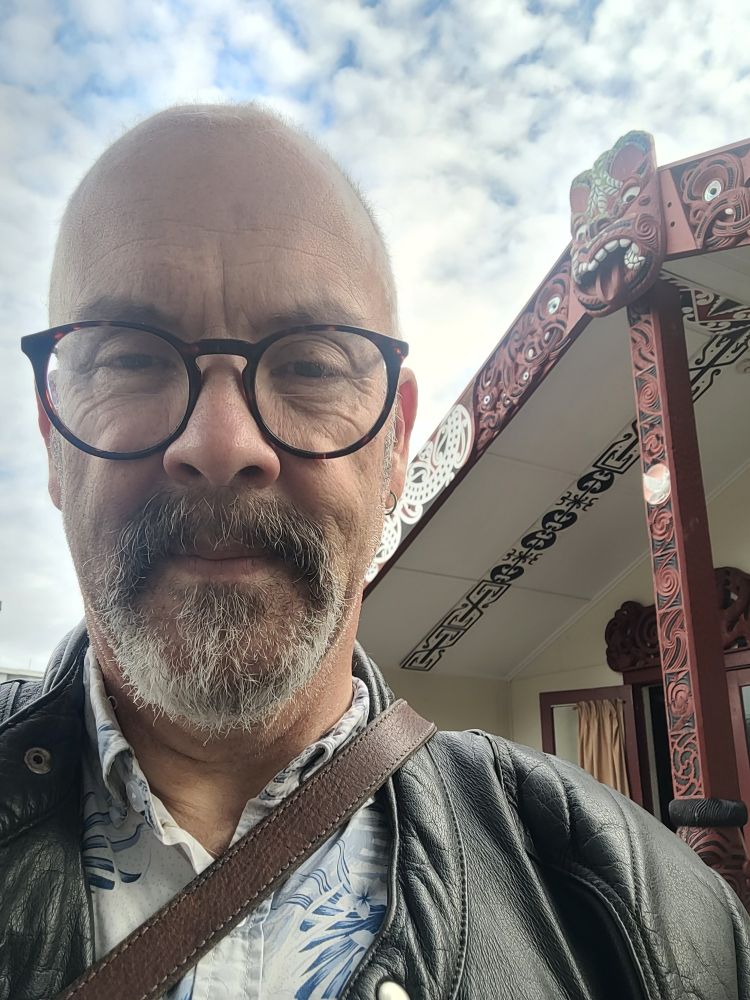 Middle aged baldy git standing outside the Waikato University Marae Te Kohinga Marama