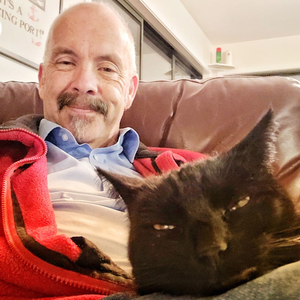 A black cat on a bald man's knee. 