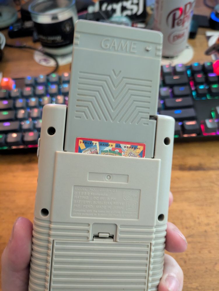 Bootleg Game Boy cartridge inserted into an original Game Boy. The cartridge is approximately twice as long as a normal Game Boy cartridge, so it sticks out really far.