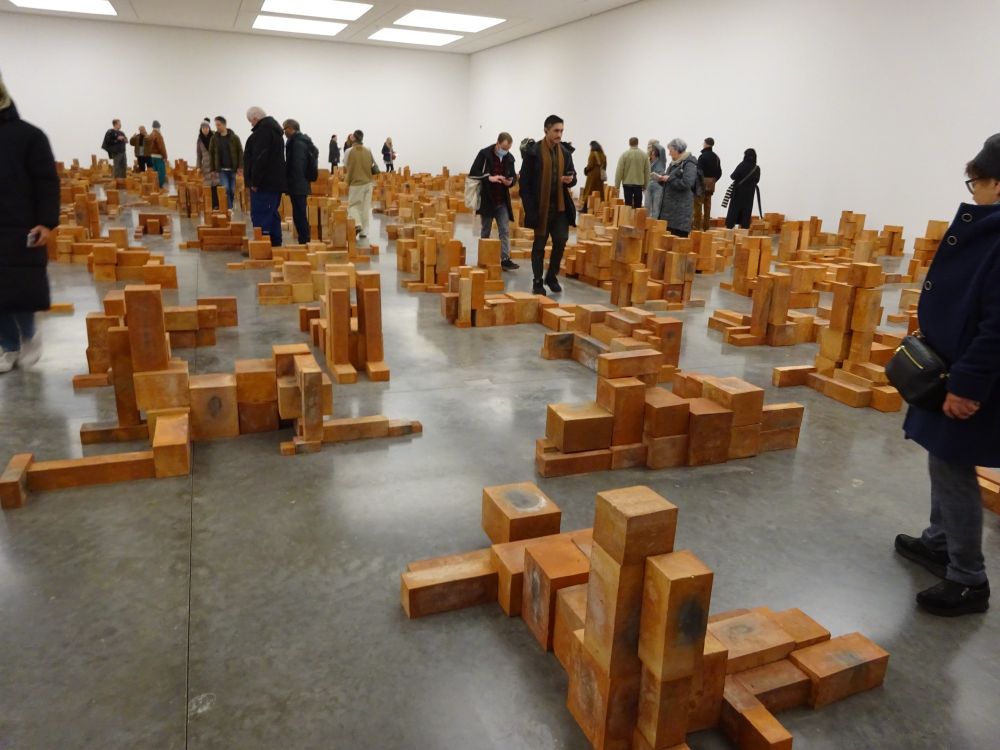 A room containing what appear to be random stacks of clay boxes, but which are on closer inspection shaped like people in various poses on the floor.