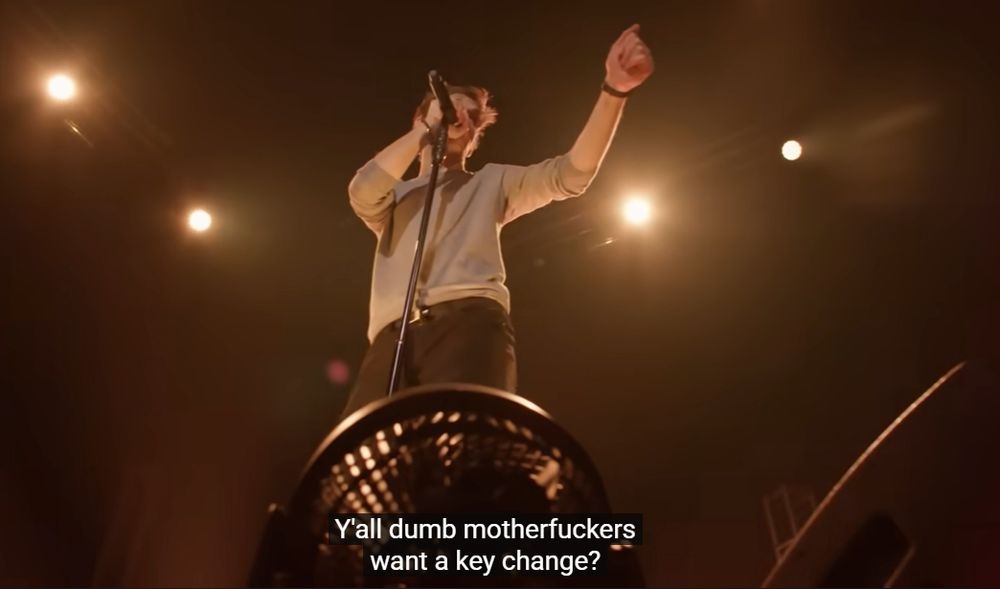 A screenshot from a Bo Burnham performance with the subtitle "Y'all dumb motherfuckers want a key change?"