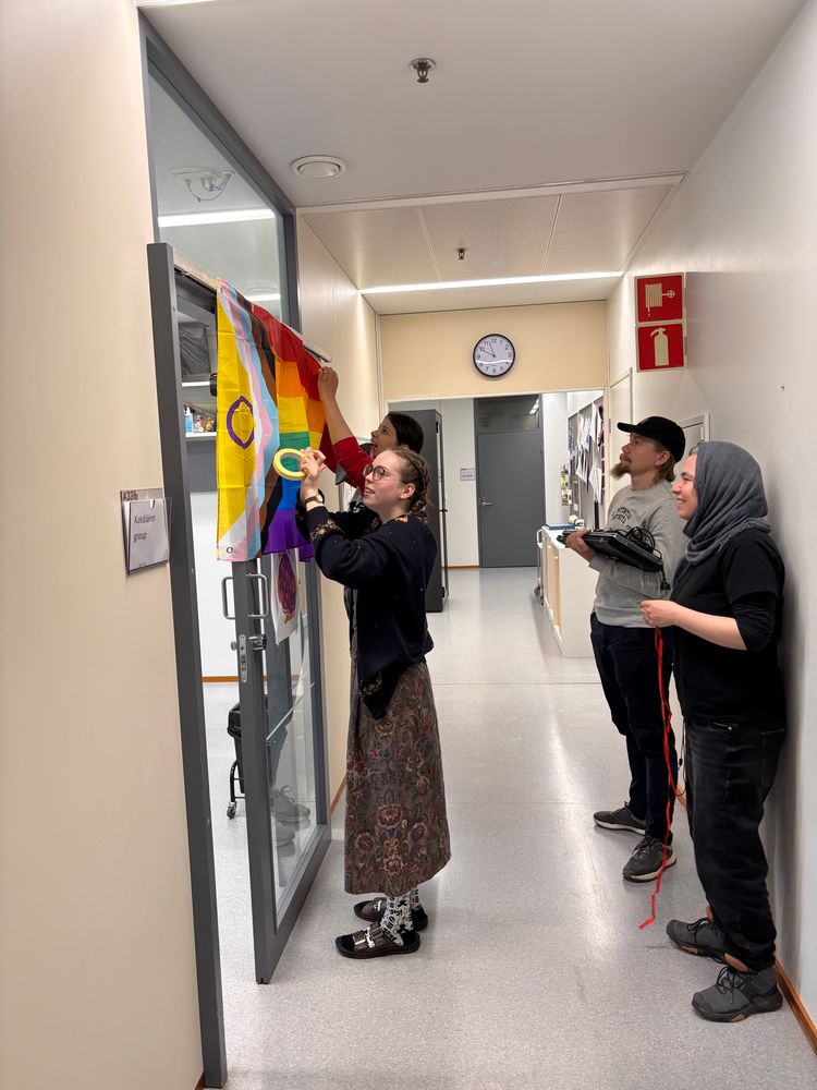 Team members raising the pride flag to our office door