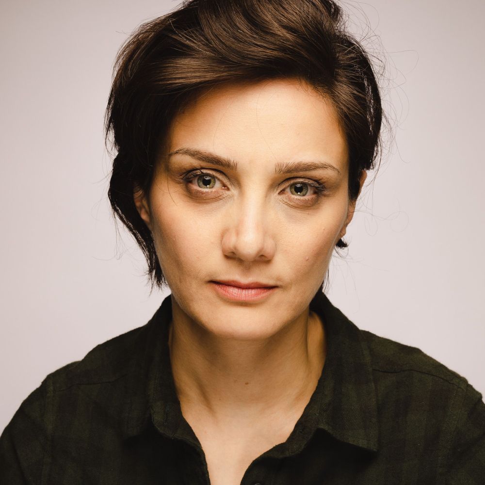 A headshot of Solmaz. She has dark brown, short hair and is wearing a dark green shirt.